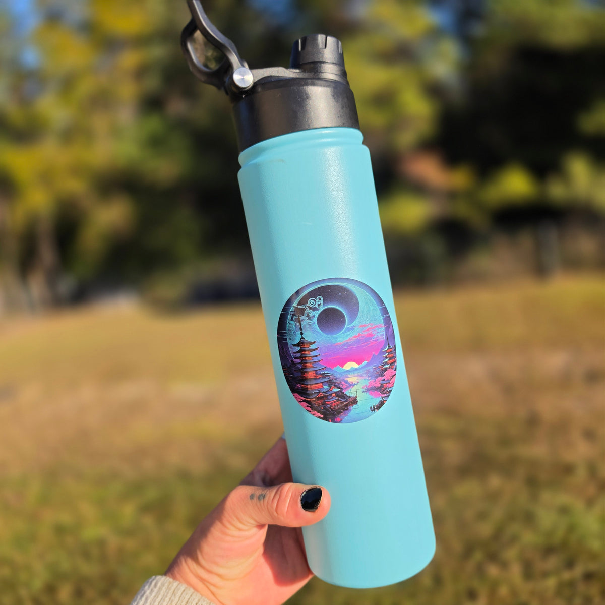 Round space and pagoda landscape sticker on a teal water bottle