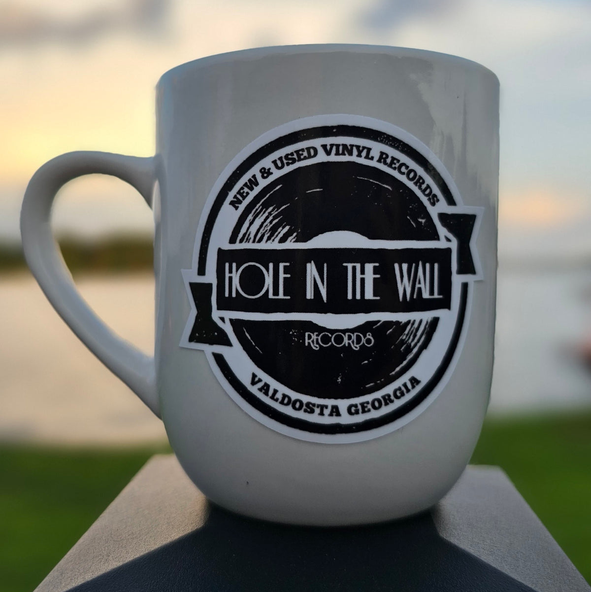 Logo sticker on a white coffee mug at sunset